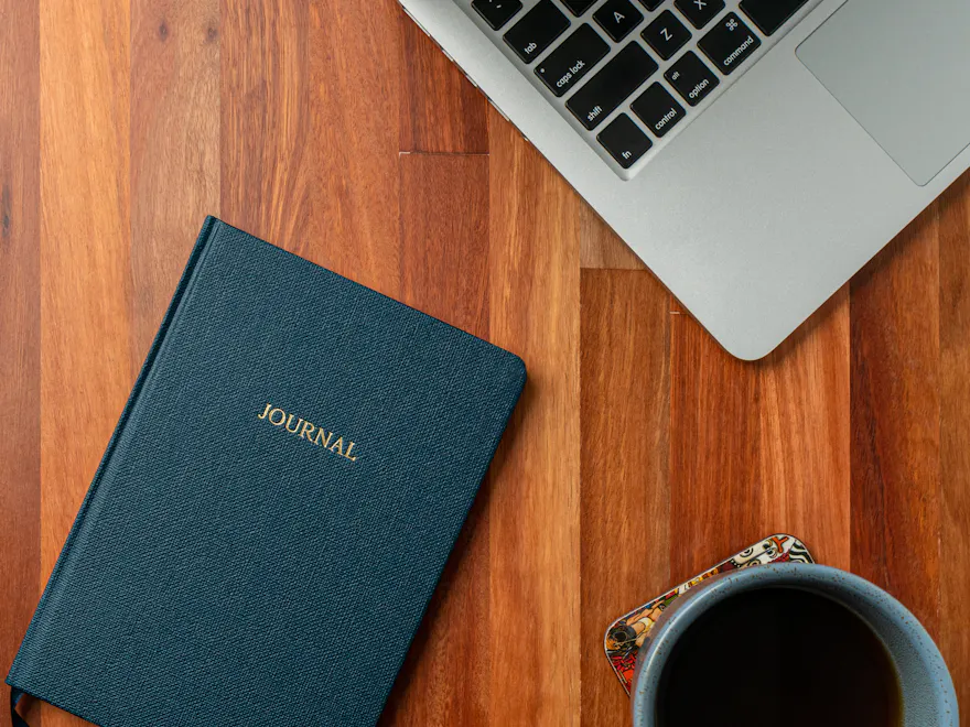 Cuaderno y portátil sobre un escritorio de madera oscura